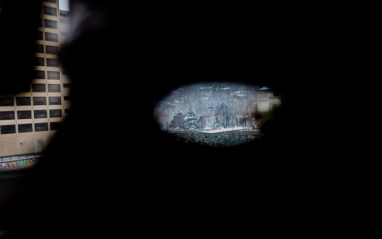 services-01 Dramatic view of a snowy cityscape through a small opening, creating a sharp contrast between urban and natural elements.